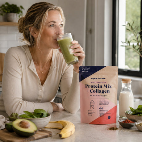 Kvinne drikker grønn proteinkokteil på kjøkken med Supernature Pretty Perfect Protein Mix + Collagen og ferske smoothieingredienser.